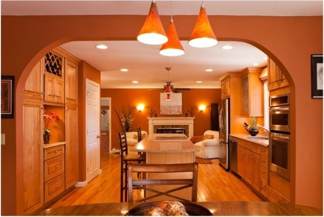 Example of a mid-sized classic u-shaped medium tone wood floor and brown floor eat-in kitchen design in Providence with a double-bowl sink, raised-panel cabinets, medium tone wood cabinets, quartz countertops, stainless steel appliances and an island