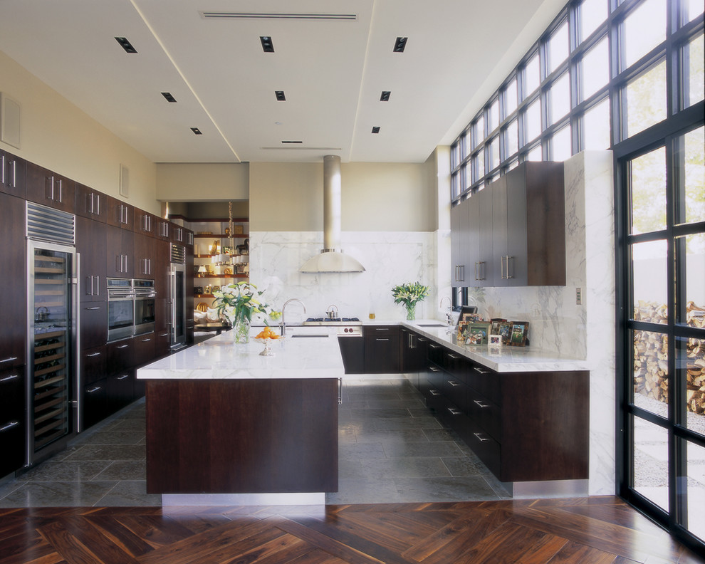 Moderne Küche mit Küchengeräten aus Edelstahl, flächenbündigen Schrankfronten, dunklen Holzschränken, Marmor-Arbeitsplatte, Küchenrückwand in Weiß, Rückwand aus Stein und grauem Boden in Miami