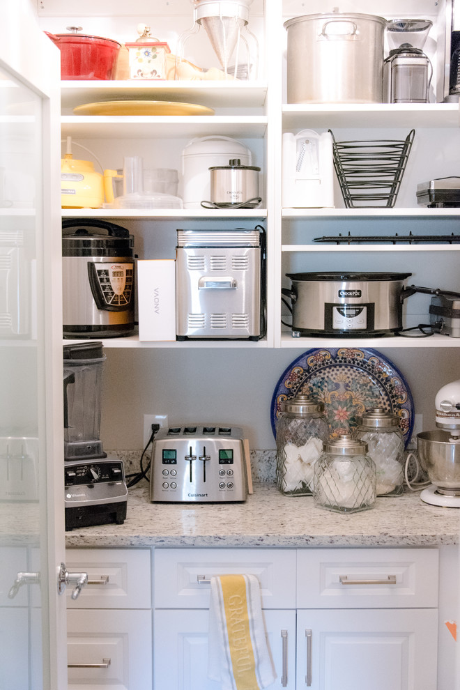 Klassisk inredning av ett mellanstort grå grått kök, med en undermonterad diskho, luckor med upphöjd panel, vita skåp, granitbänkskiva, vitt stänkskydd, stänkskydd i tunnelbanekakel, rostfria vitvaror, klinkergolv i keramik, en köksö och beiget golv