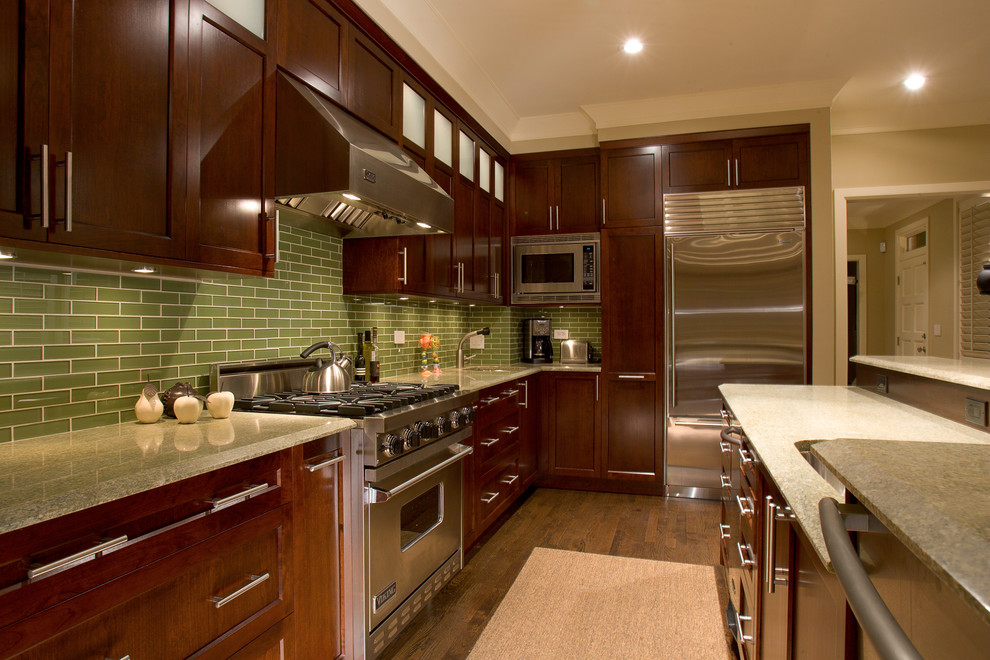 Moderne Küche mit Küchengeräten aus Edelstahl, Schrankfronten mit vertiefter Füllung, dunklen Holzschränken, Granit-Arbeitsplatte und Küchenrückwand in Grün in Chicago