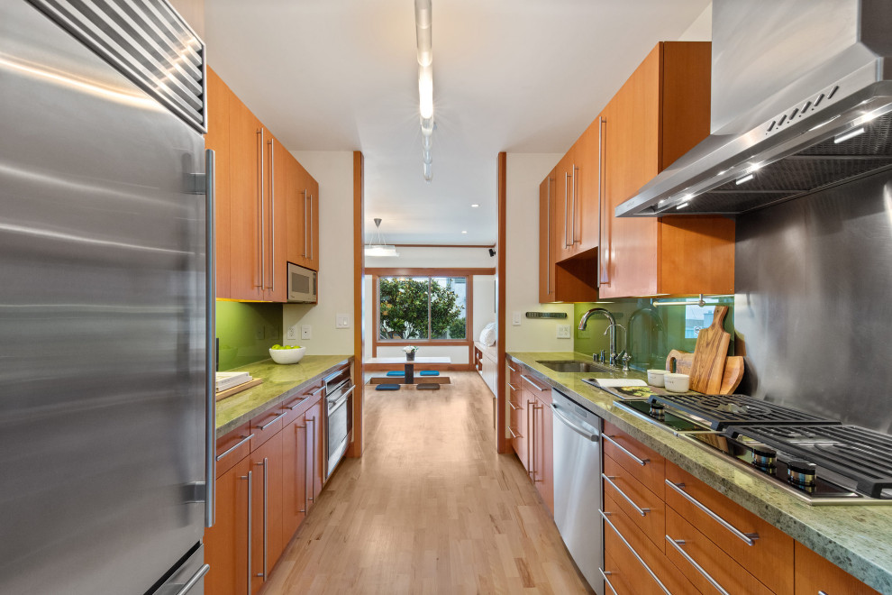 サンフランシスコにある高級な小さなアジアンスタイルのおしゃれなキッチン (シングルシンク、フラットパネル扉のキャビネット、淡色木目調キャビネット、大理石カウンター、緑のキッチンパネル、ガラス板のキッチンパネル、シルバーの調理設備、淡色無垢フローリング、アイランドなし、ベージュの床、緑のキッチンカウンター) の写真