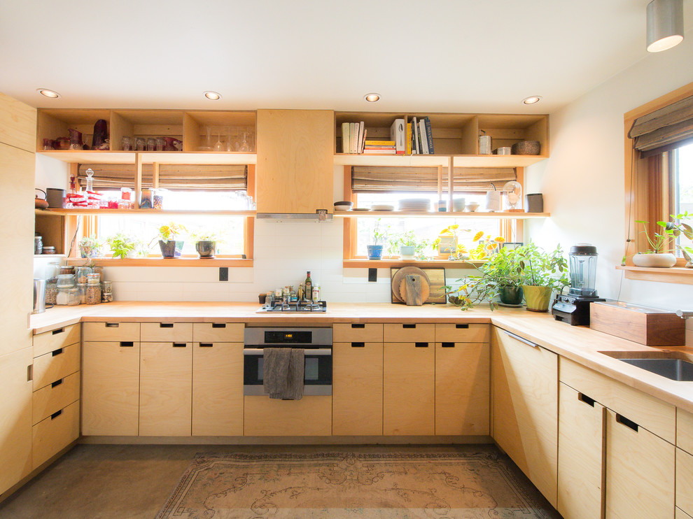 Foto på ett orientaliskt brun u-kök, med en undermonterad diskho, släta luckor, skåp i ljust trä, träbänkskiva, vitt stänkskydd, rostfria vitvaror, betonggolv och grått golv