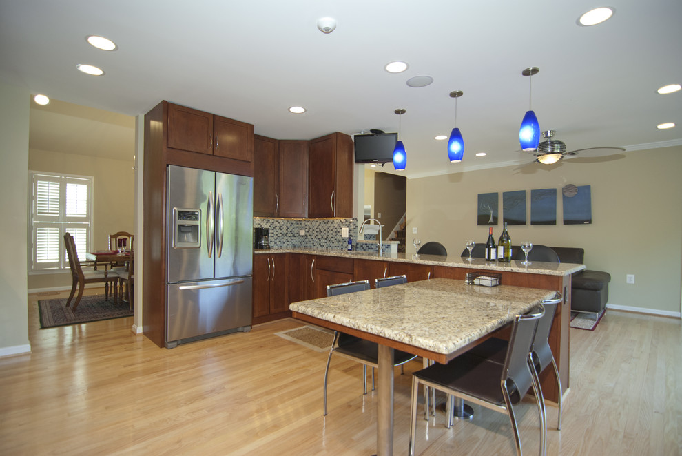 Modelo de cocina actual con puertas de armario de madera en tonos medios, salpicadero con mosaicos de azulejos y electrodomésticos de acero inoxidable