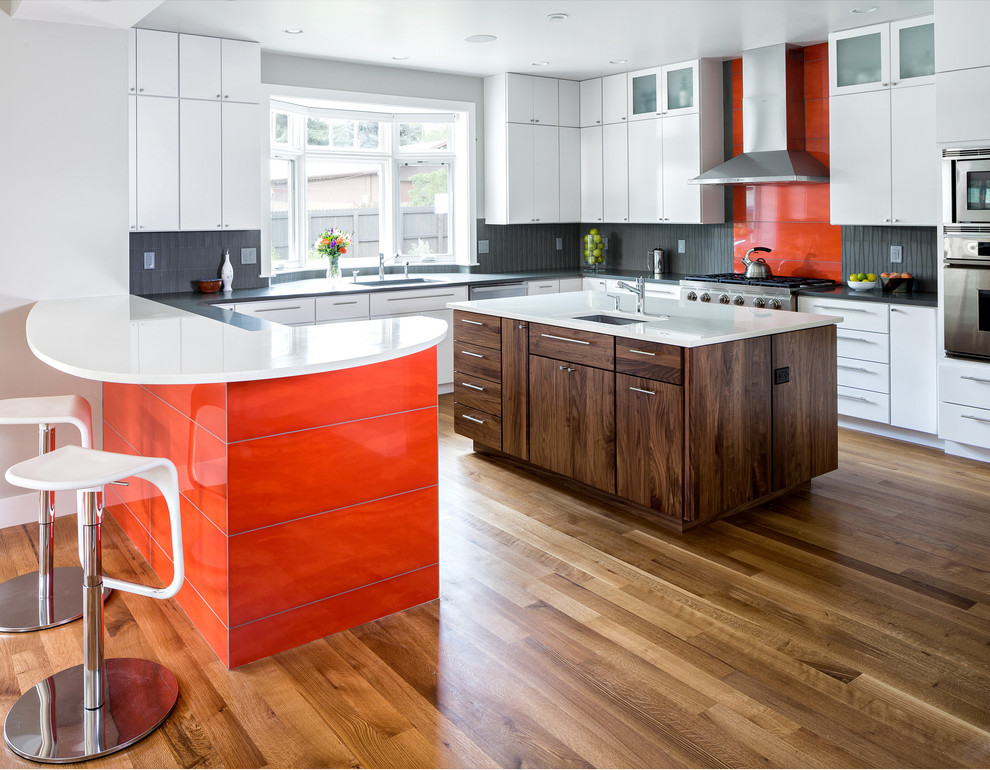 Moderne Küche mit flächenbündigen Schrankfronten, weißen Schränken, Küchenrückwand in Orange und Küchengeräten aus Edelstahl in Denver