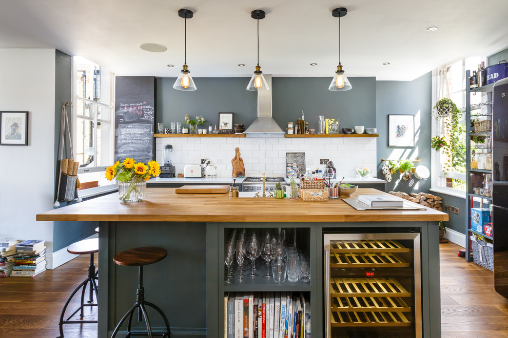 Nordische Küche mit Küchenrückwand in Weiß, Rückwand aus Metrofliesen, Küchengeräten aus Edelstahl, braunem Holzboden, Kücheninsel, braunem Boden und weißer Arbeitsplatte in London