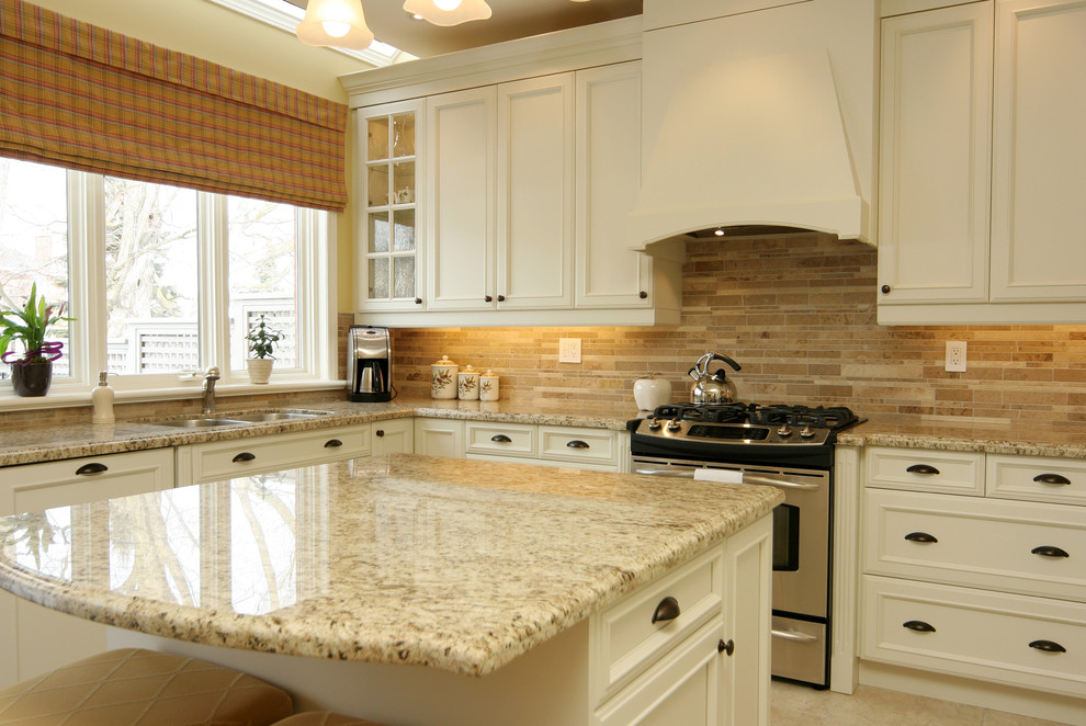 Inspiration for a mid-sized timeless u-shaped ceramic tile kitchen remodel in Toronto with granite countertops, a double-bowl sink, recessed-panel cabinets, white cabinets, brown backsplash, stainless steel appliances, stone tile backsplash and an island