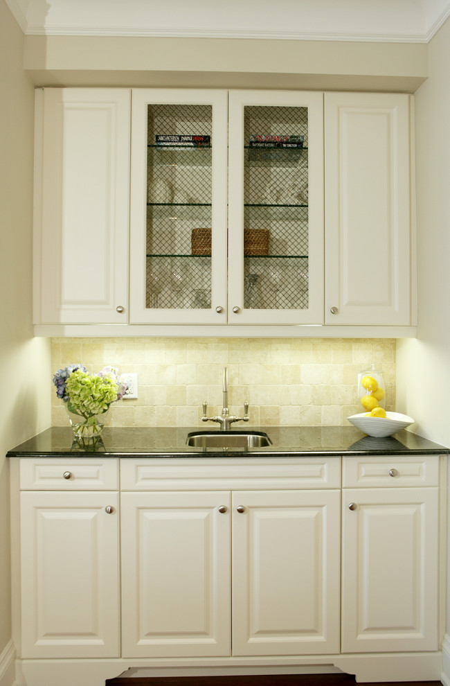 Klassisk inredning av ett mellanstort kök, med en undermonterad diskho, luckor med glaspanel, vita skåp, beige stänkskydd, mörkt trägolv, bänkskiva i kvartsit och stänkskydd i stenkakel