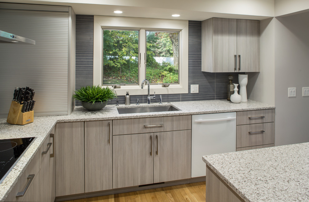 Photo of a medium sized contemporary u-shaped kitchen/diner in Grand Rapids with a submerged sink, flat-panel cabinets, grey cabinets, engineered stone countertops, grey splashback, porcelain splashback, white appliances, medium hardwood flooring and an island.