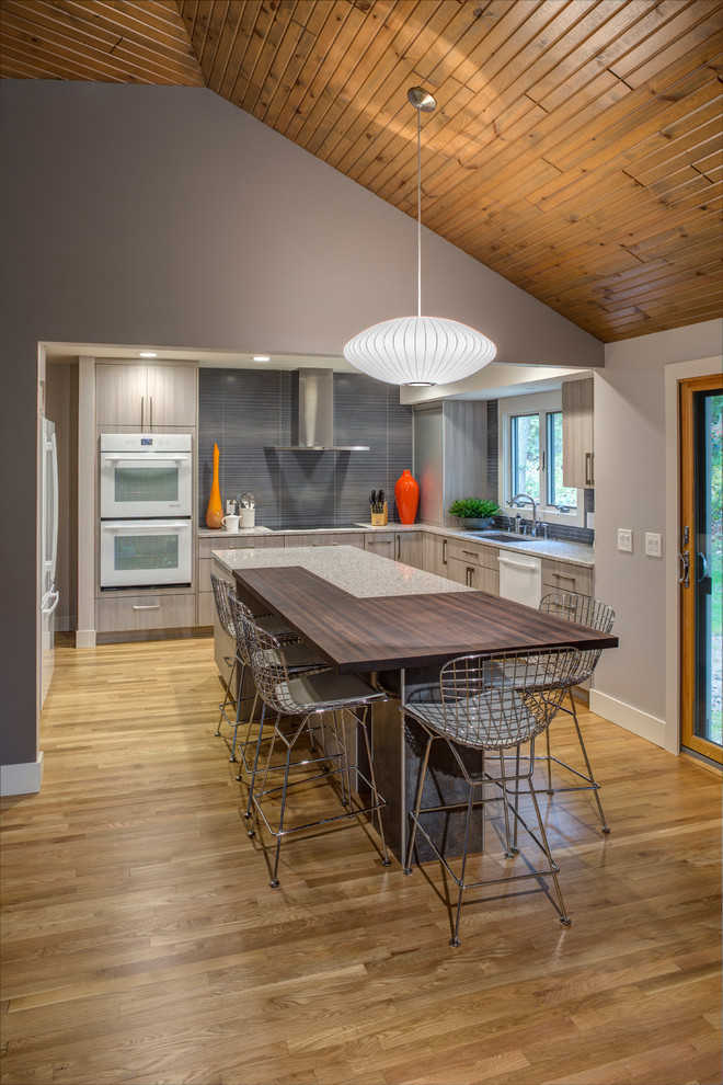 Inspiration for a mid-sized contemporary u-shaped medium tone wood floor eat-in kitchen remodel in Grand Rapids with an undermount sink, flat-panel cabinets, gray cabinets, quartz countertops, gray backsplash, porcelain backsplash, white appliances and an island