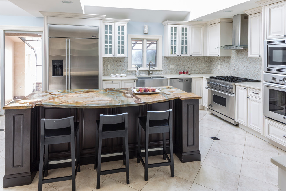 Large transitional l-shaped ceramic tile kitchen photo in New York with a farmhouse sink, raised-panel cabinets, white cabinets, solid surface countertops, gray backsplash, mosaic tile backsplash, stainless steel appliances and an island