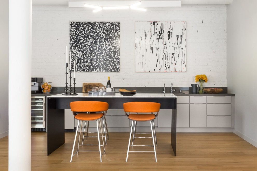 Einzeilige Moderne Küche mit Unterbauwaschbecken, flächenbündigen Schrankfronten, Küchenrückwand in Weiß, Rückwand aus Backstein, hellem Holzboden und Kücheninsel in San Francisco