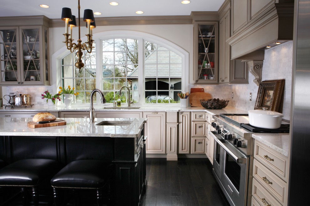 Inspiration for a mid-sized timeless l-shaped dark wood floor kitchen remodel in St Louis with glass-front cabinets, an undermount sink, beige cabinets, granite countertops, white backsplash, stone tile backsplash and stainless steel appliances