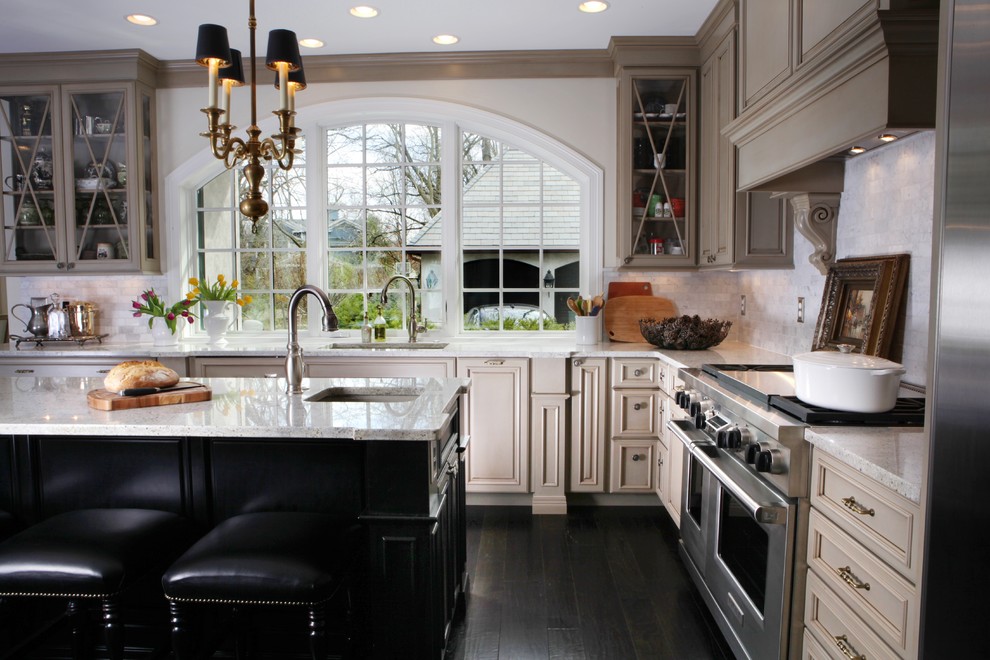 Exempel på ett mellanstort klassiskt l-kök, med luckor med glaspanel, en undermonterad diskho, beige skåp, granitbänkskiva, vitt stänkskydd, stänkskydd i stenkakel, rostfria vitvaror och mörkt trägolv