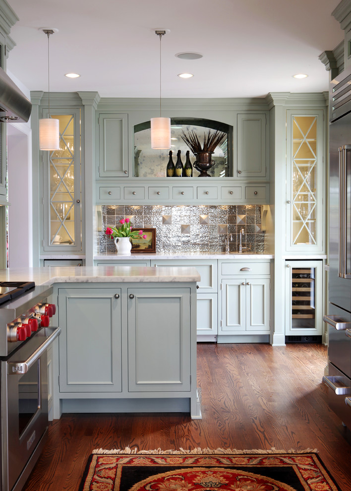 Example of a mid-sized classic u-shaped medium tone wood floor enclosed kitchen design in St Louis with stainless steel appliances, an undermount sink, recessed-panel cabinets, green cabinets, marble countertops, metallic backsplash and metal backsplash