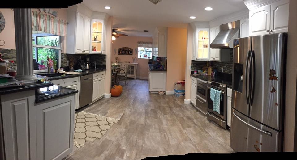 Example of a mid-sized beach style eat-in kitchen design in Miami with white cabinets