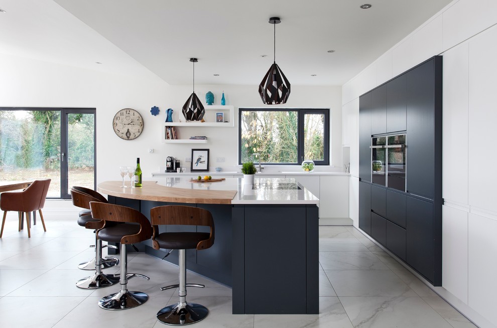 Inspiration pour une cuisine ouverte bicolore design en L avec un placard à porte plane, des portes de placard noires, une crédence blanche, un électroménager noir et îlot.