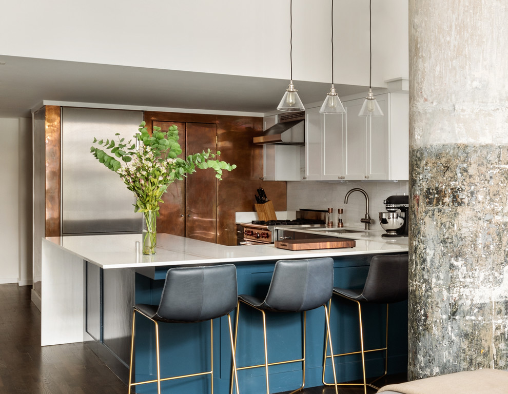 Inspiration for a medium sized bohemian u-shaped open plan kitchen in New York with a submerged sink, shaker cabinets, blue cabinets, marble worktops, white splashback, marble splashback, stainless steel appliances, medium hardwood flooring, a breakfast bar, brown floors and white worktops.