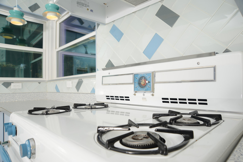Foto på ett mellanstort 60 tals kök, med en integrerad diskho, släta luckor, laminatbänkskiva, stänkskydd i glaskakel, blå skåp, beige stänkskydd, linoleumgolv och beiget golv