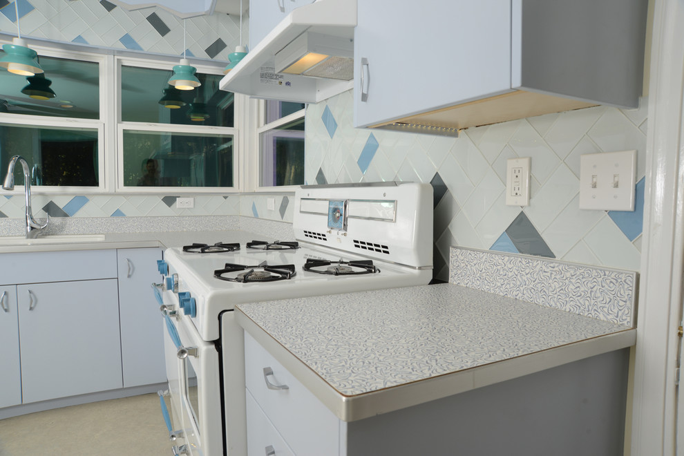Inspiration for a medium sized retro u-shaped kitchen/diner in Miami with an integrated sink, flat-panel cabinets, laminate countertops, glass tiled splashback, blue cabinets, beige splashback, lino flooring, no island and beige floors.