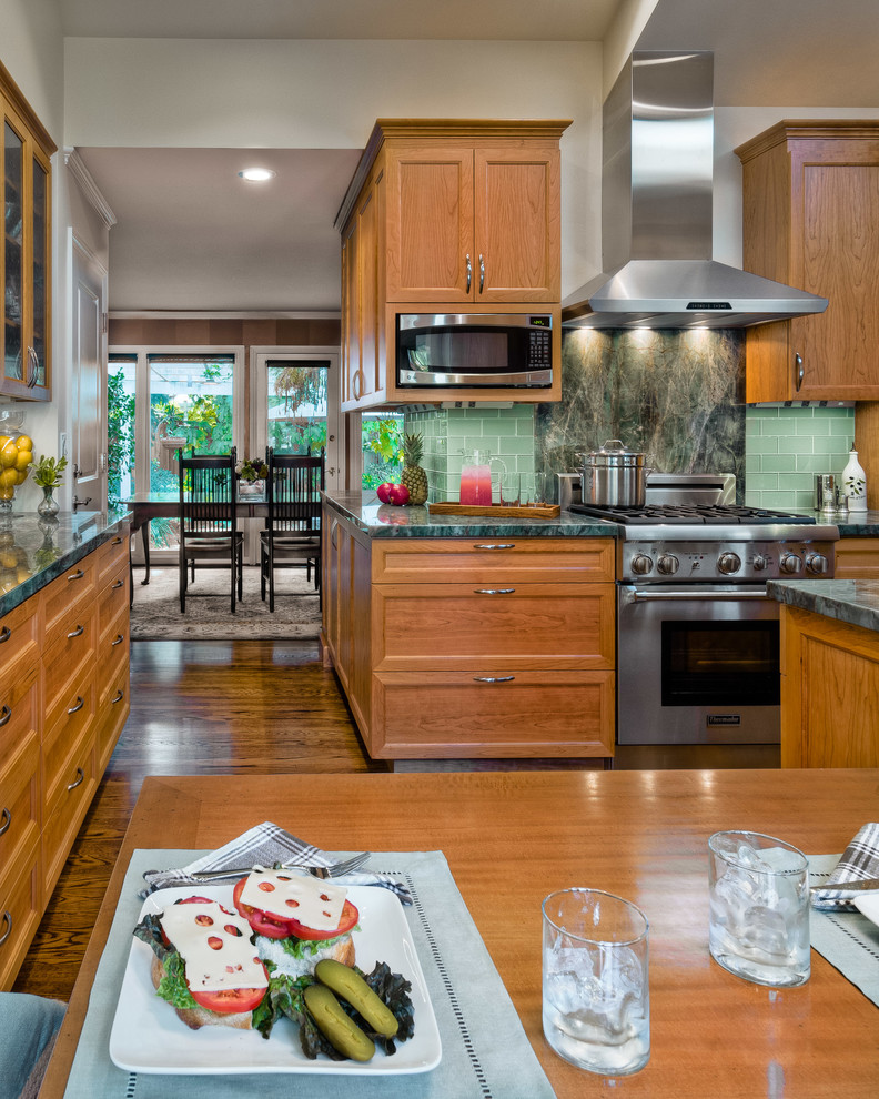 Exempel på ett mellanstort klassiskt kök, med en undermonterad diskho, luckor med infälld panel, skåp i mellenmörkt trä, bänkskiva i kvartsit, grönt stänkskydd, stänkskydd i glaskakel, rostfria vitvaror och mellanmörkt trägolv