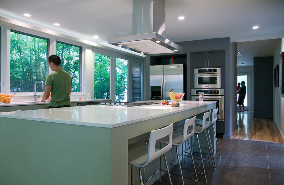 Imagen de cocina actual con electrodomésticos de acero inoxidable, puertas de armario verdes y barras de cocina
