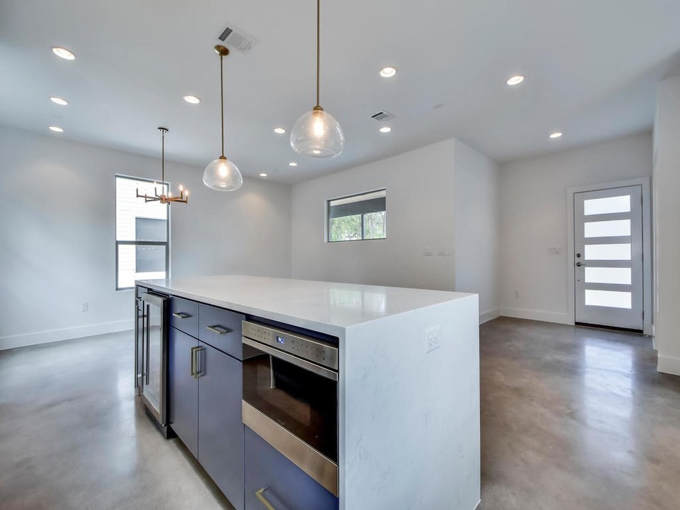 Bild på ett mellanstort funkis vit vitt kök, med en rustik diskho, släta luckor, vita skåp, marmorbänkskiva, grått stänkskydd, stänkskydd i porslinskakel, rostfria vitvaror, betonggolv, en köksö och grått golv
