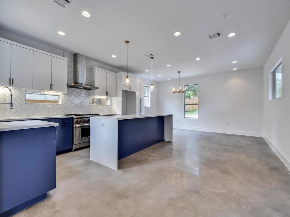 Example of a mid-sized minimalist l-shaped concrete floor and gray floor open concept kitchen design in Austin with a farmhouse sink, flat-panel cabinets, white cabinets, marble countertops, gray backsplash, porcelain backsplash, stainless steel appliances, an island and white countertops