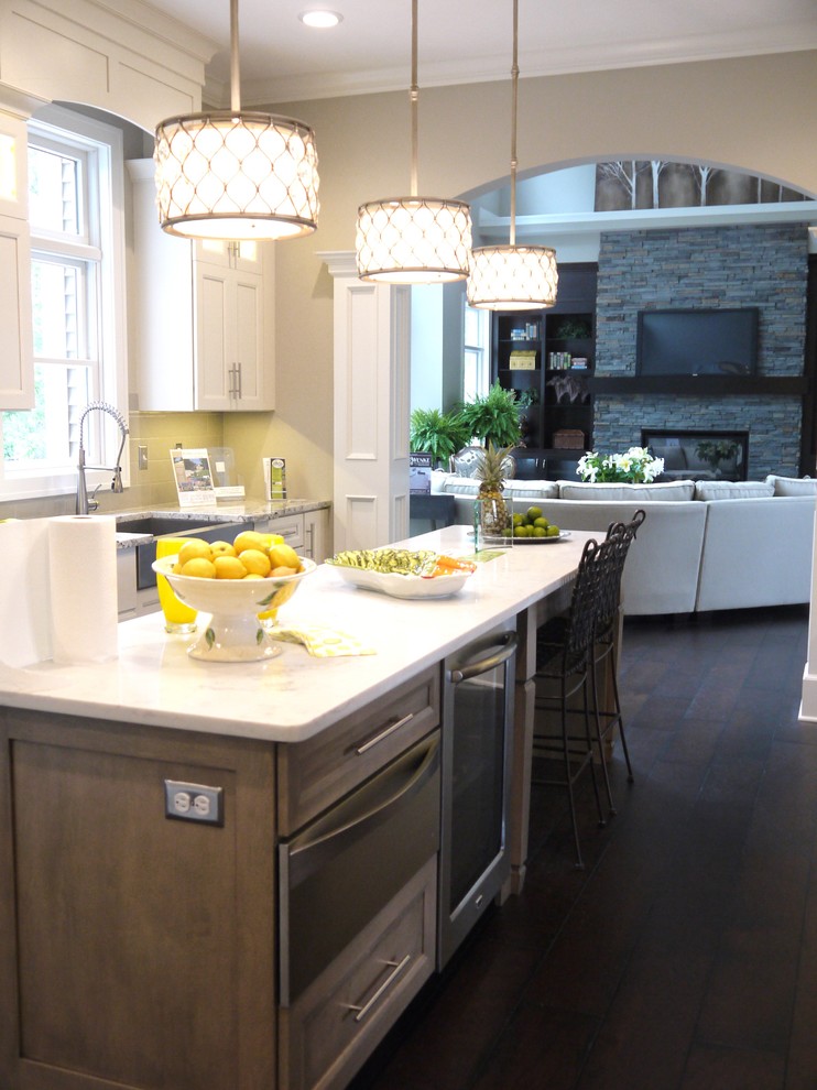 This is an example of a large classic galley kitchen in Grand Rapids with a belfast sink, recessed-panel cabinets, distressed cabinets, quartz worktops, grey splashback, metro tiled splashback, stainless steel appliances, dark hardwood flooring and an island.
