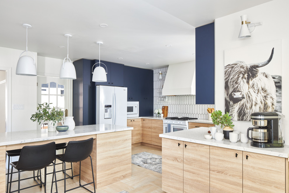 Foto på ett mellanstort funkis vit kök, med släta luckor, blå skåp, bänkskiva i kvarts, vitt stänkskydd, stänkskydd i porslinskakel, vita vitvaror, klinkergolv i porslin, en köksö och beiget golv
