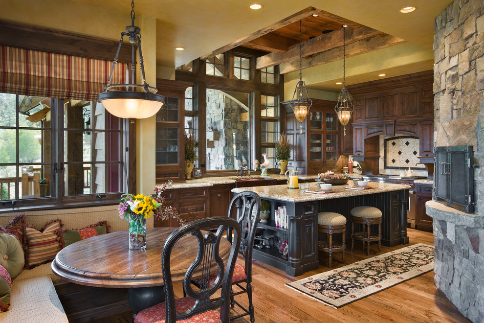 Example of a mountain style l-shaped eat-in kitchen design in Other with a farmhouse sink, recessed-panel cabinets, multicolored backsplash, mosaic tile backsplash, stainless steel appliances and dark wood cabinets