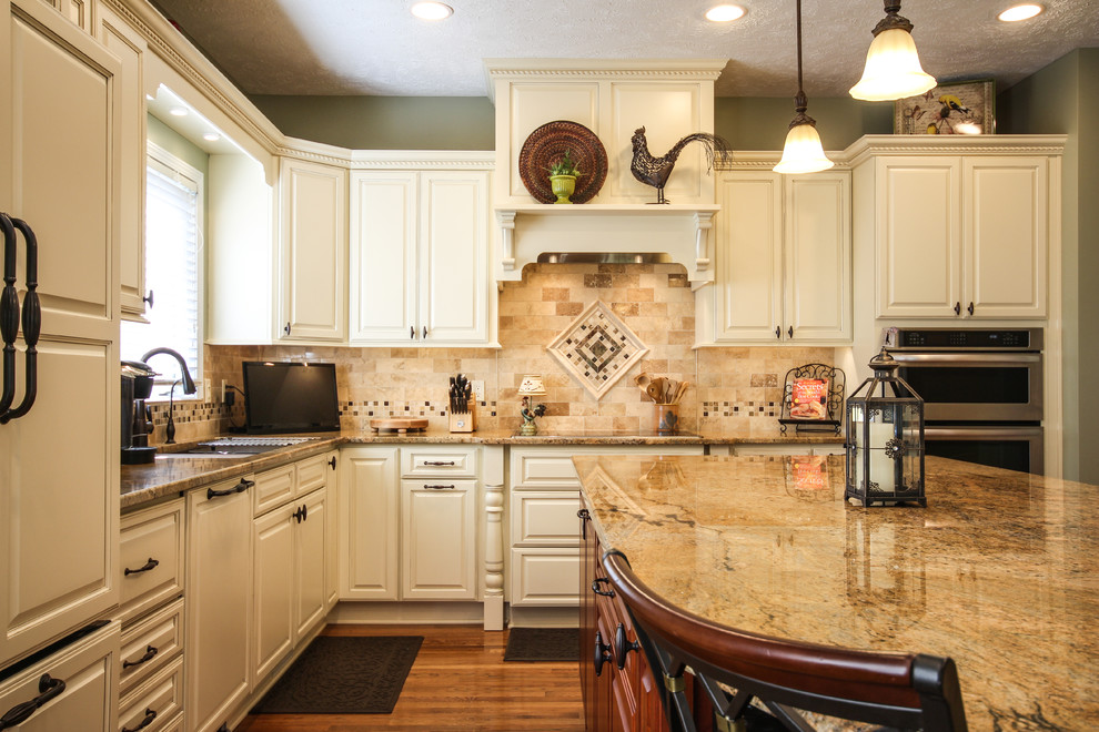 Elegant kitchen photo in Detroit with an undermount sink, raised-panel cabinets, white cabinets, granite countertops, beige backsplash, stone tile backsplash and paneled appliances
