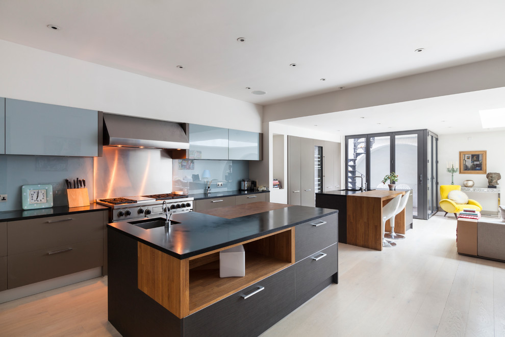 Photo of a large contemporary galley open plan kitchen in London with a submerged sink, flat-panel cabinets, brown cabinets, metallic splashback, stainless steel appliances, light hardwood flooring and an island.
