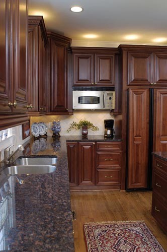 Exempel på ett stort klassiskt kök, med en undermonterad diskho, luckor med infälld panel, skåp i mörkt trä, granitbänkskiva, beige stänkskydd, stänkskydd i stenkakel, rostfria vitvaror, mellanmörkt trägolv och en köksö
