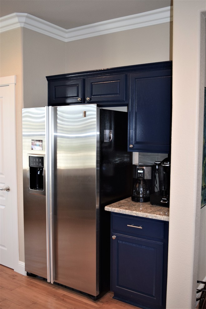 Inredning av ett klassiskt mellanstort beige beige kök, med en undermonterad diskho, luckor med upphöjd panel, blå skåp, granitbänkskiva, grått stänkskydd, stänkskydd i glaskakel, rostfria vitvaror, mellanmörkt trägolv och en halv köksö