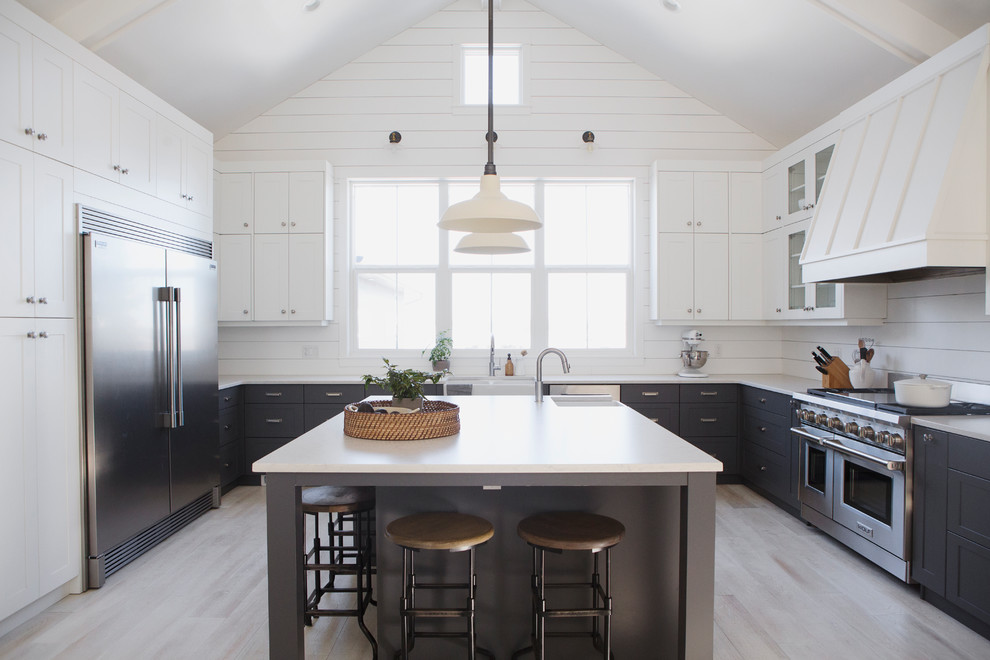 Example of a mid-sized cottage u-shaped light wood floor kitchen design with shaker cabinets, an island, white backsplash and stainless steel appliances