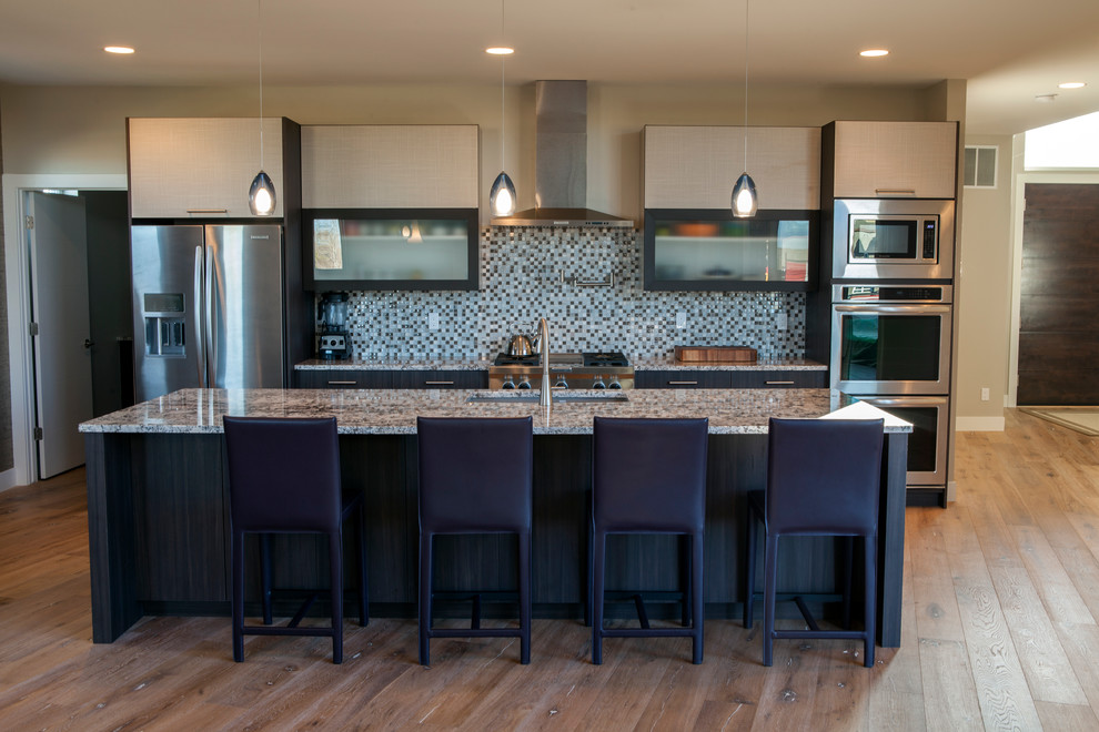 Mid-sized trendy galley light wood floor and brown floor open concept kitchen photo in Denver with an undermount sink, flat-panel cabinets, dark wood cabinets, granite countertops, multicolored backsplash, glass tile backsplash, stainless steel appliances and an island