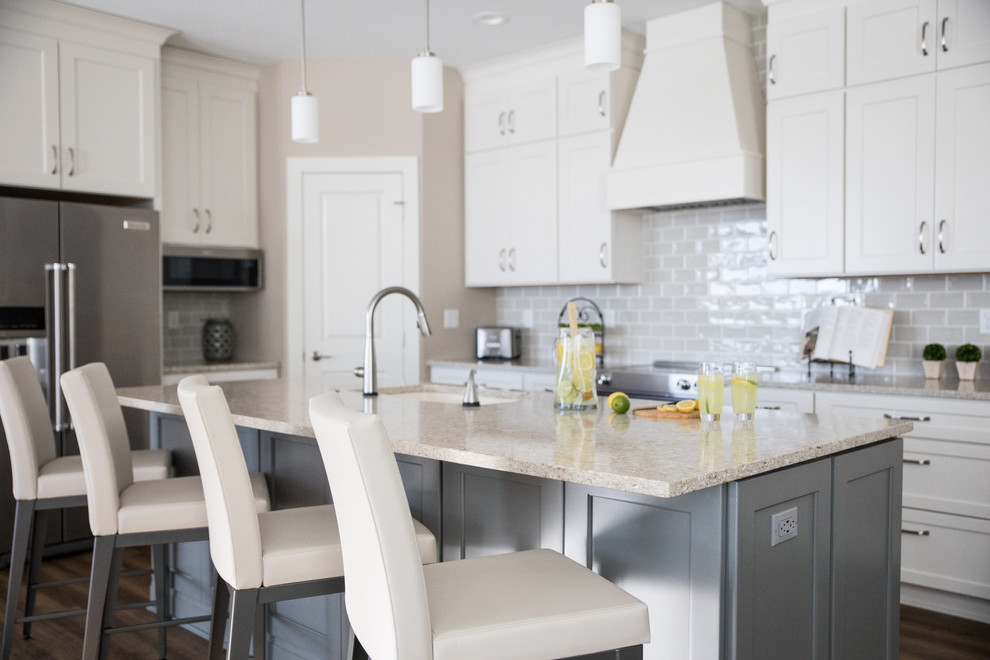 Exempel på ett stort klassiskt flerfärgad flerfärgat kök, med en undermonterad diskho, luckor med infälld panel, vita skåp, bänkskiva i kvarts, grått stänkskydd, stänkskydd i tunnelbanekakel, rostfria vitvaror, vinylgolv, en köksö och brunt golv