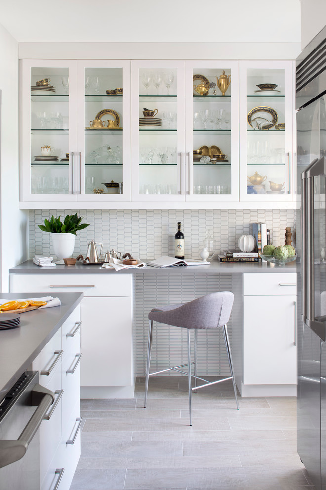 Cette photo montre une cuisine tendance avec un placard à porte vitrée, des portes de placard blanches, une crédence blanche, un électroménager en acier inoxydable, un sol en carrelage de porcelaine et un sol gris.