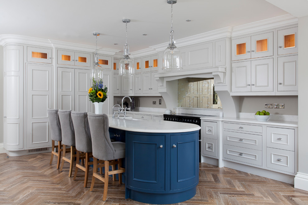 Transitional l-shaped medium tone wood floor and brown floor kitchen photo in Dublin with a farmhouse sink, beaded inset cabinets, blue cabinets, mirror backsplash, black appliances, an island and white countertops