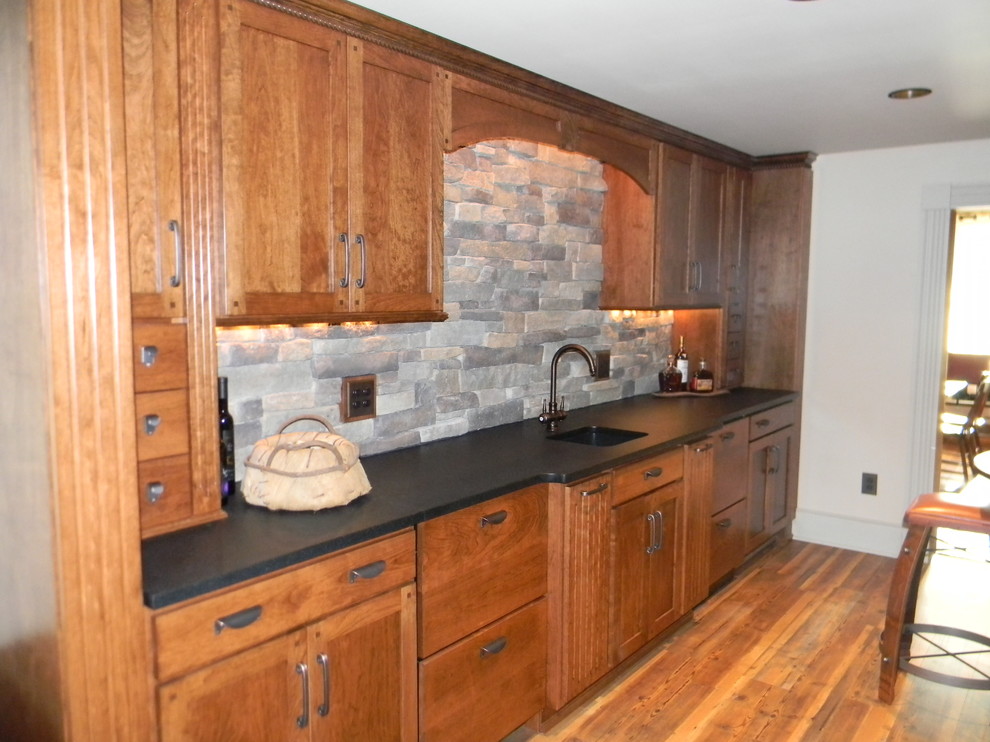Idées déco pour une petite cuisine parallèle campagne en bois brun avec un évier encastré, un placard à porte shaker, un plan de travail en granite, une crédence grise, une crédence en carrelage de pierre et un sol en bois brun.