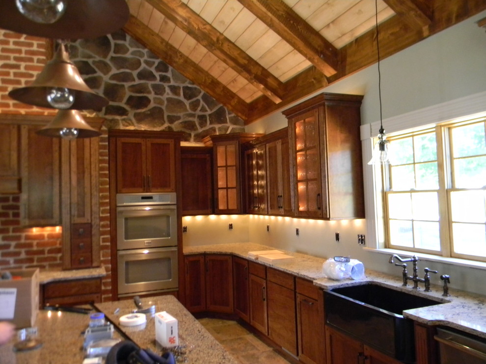 Inredning av ett lantligt stort kök, med en rustik diskho, skåp i shakerstil, skåp i mellenmörkt trä, granitbänkskiva, beige stänkskydd, stänkskydd i stenkakel, rostfria vitvaror, klinkergolv i porslin och en köksö