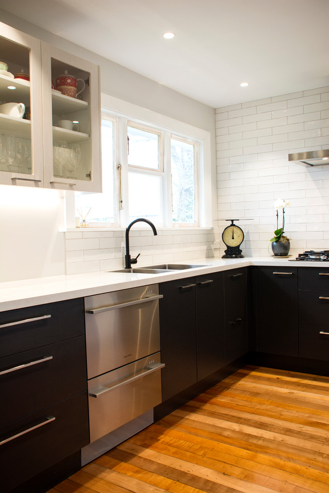 Exempel på ett mellanstort modernt kök, med en dubbel diskho, svarta skåp, laminatbänkskiva, vitt stänkskydd, stänkskydd i tunnelbanekakel, rostfria vitvaror och mellanmörkt trägolv