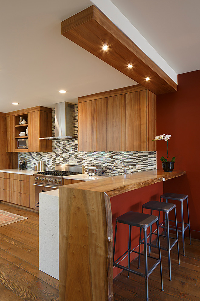 Foto på ett funkis kök, med rostfria vitvaror, träbänkskiva och flerfärgad stänkskydd