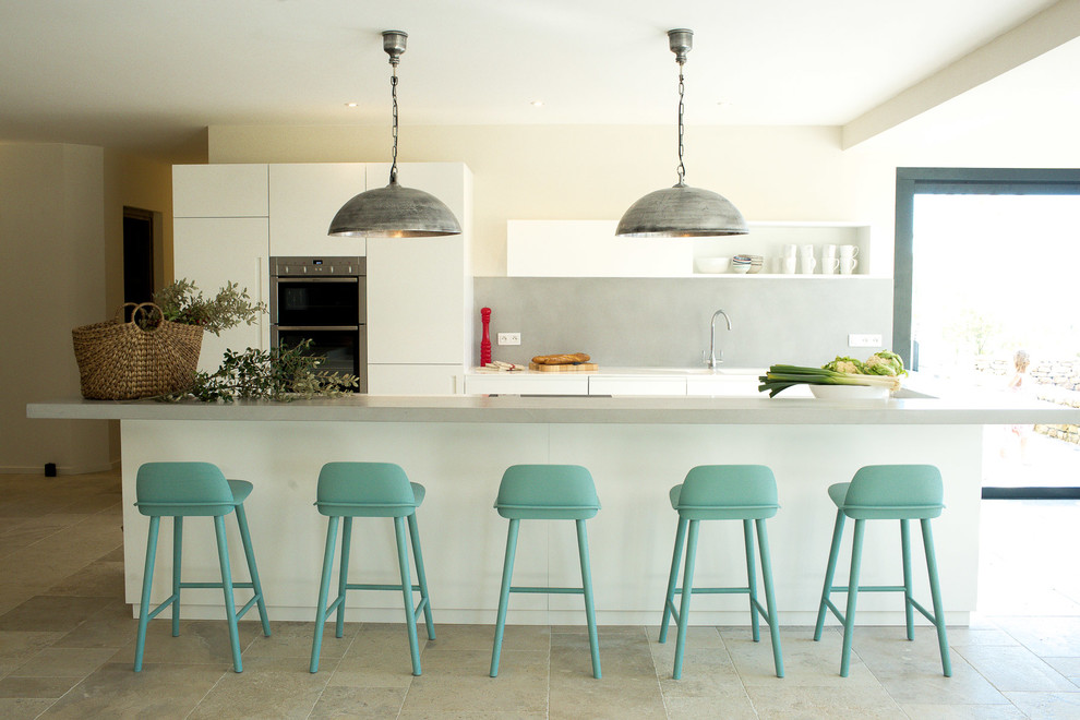 Стильный дизайн: большая параллельная кухня в современном стиле с обеденным столом, белыми фасадами, серым фартуком и островом - последний тренд