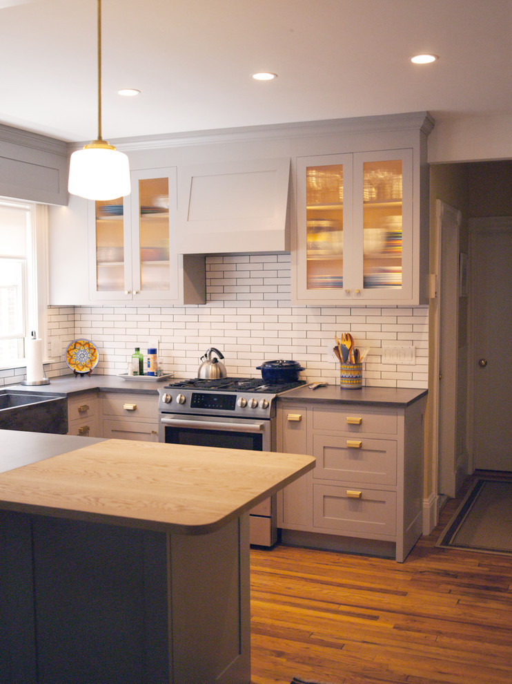 Photo of a small u-shaped kitchen/diner in Boston with a belfast sink, glass-front cabinets, grey cabinets, concrete worktops, white splashback, metro tiled splashback, stainless steel appliances, medium hardwood flooring, no island, brown floors and grey worktops.