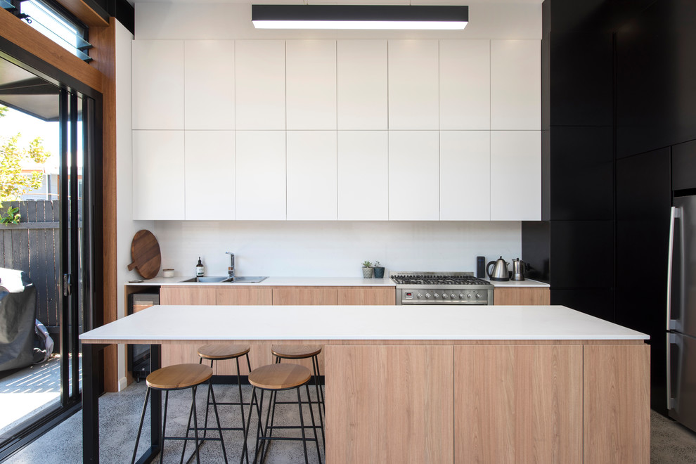 Inspiration för mellanstora moderna linjära vitt kök och matrum, med släta luckor, vitt stänkskydd, rostfria vitvaror, betonggolv, en köksö, grått golv, en dubbel diskho och vita skåp
