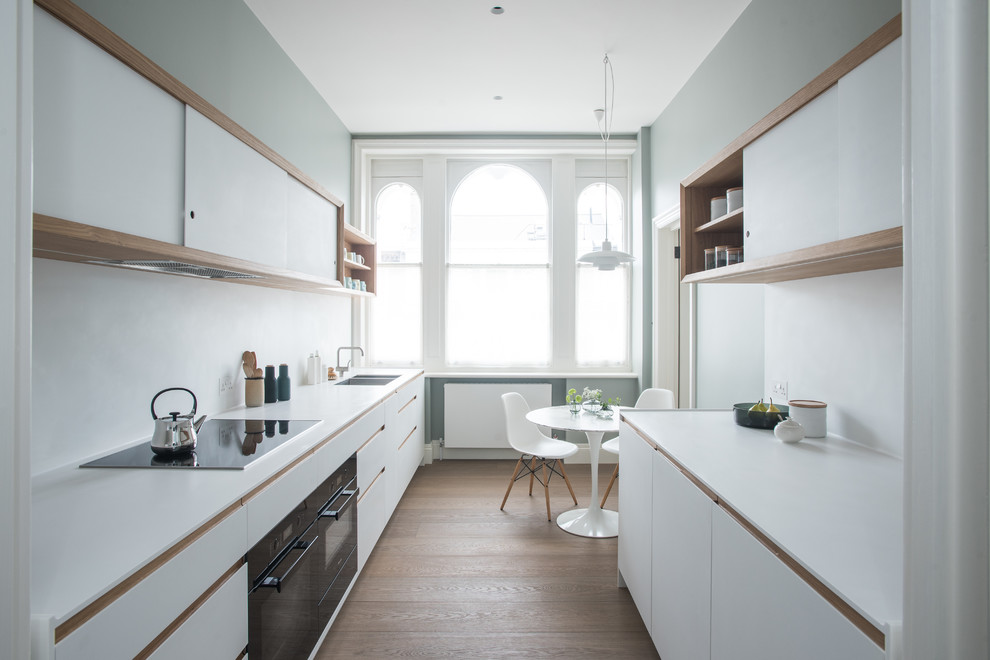 Small contemporary galley enclosed kitchen in London with white cabinets.