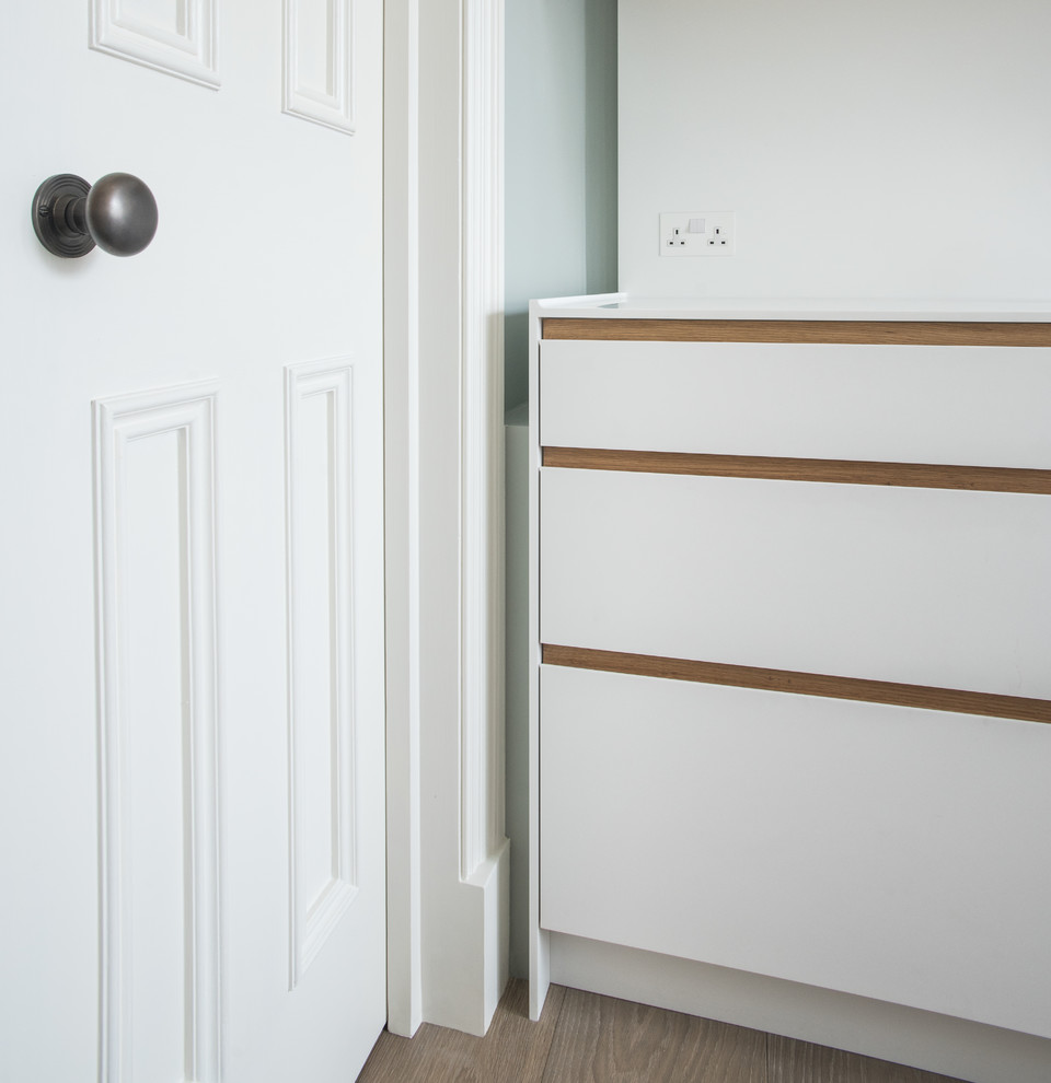 Idée de décoration pour une petite cuisine parallèle design fermée avec des portes de placard blanches.