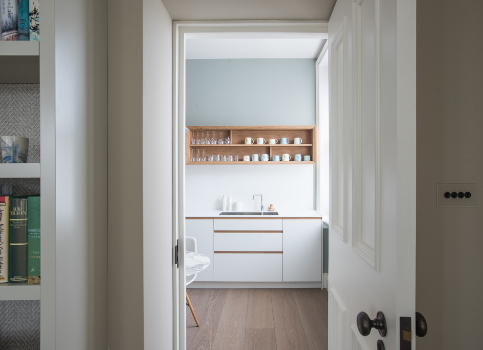 Cette image montre une petite cuisine parallèle design fermée avec des portes de placard blanches.