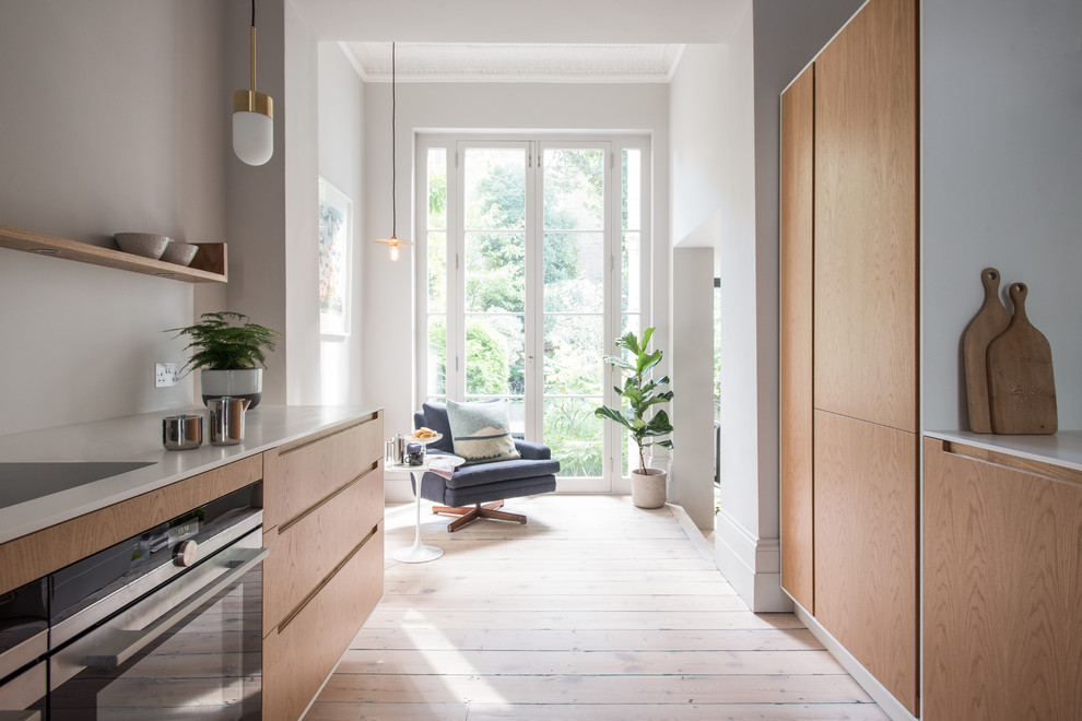Zweizeilige, Mittelgroße Moderne Wohnküche mit Küchenrückwand in Weiß, hellem Holzboden, Unterbauwaschbecken, flächenbündigen Schrankfronten, hellen Holzschränken, Quarzit-Arbeitsplatte, Elektrogeräten mit Frontblende und braunem Boden in London